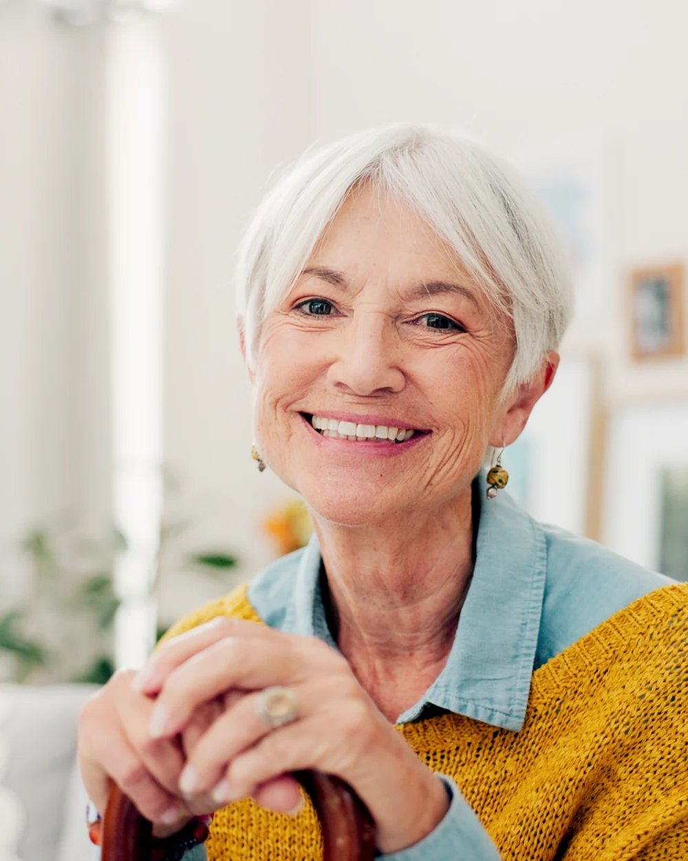 Smiling older woman in a yellow sweater at home