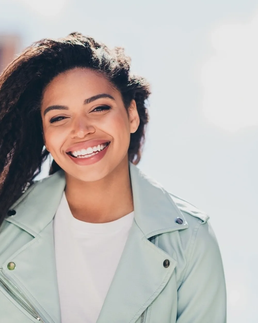 Smiling woman outdoors after a comfortable dental visit