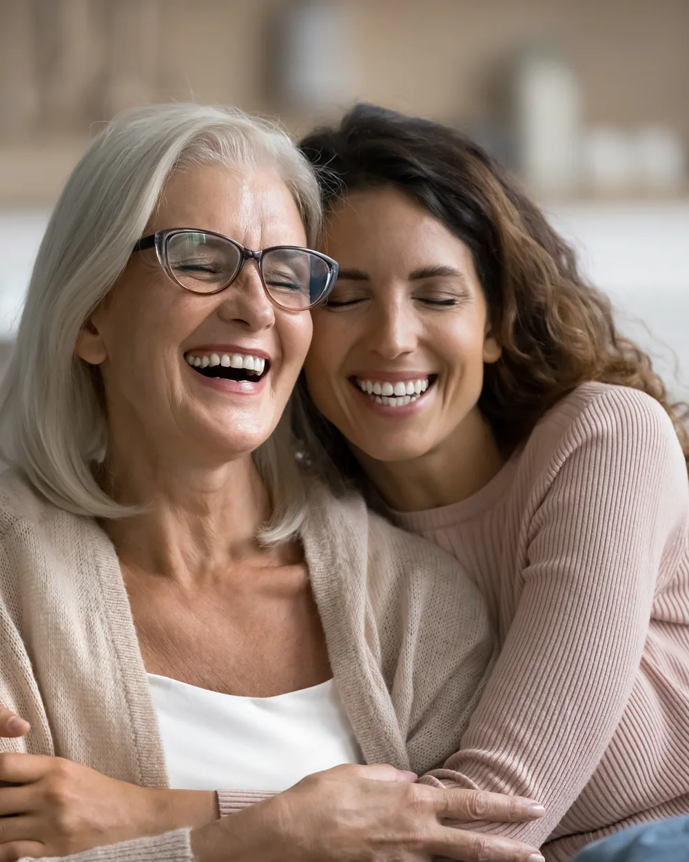 Smiling older woman and adult daughter seated on a couch