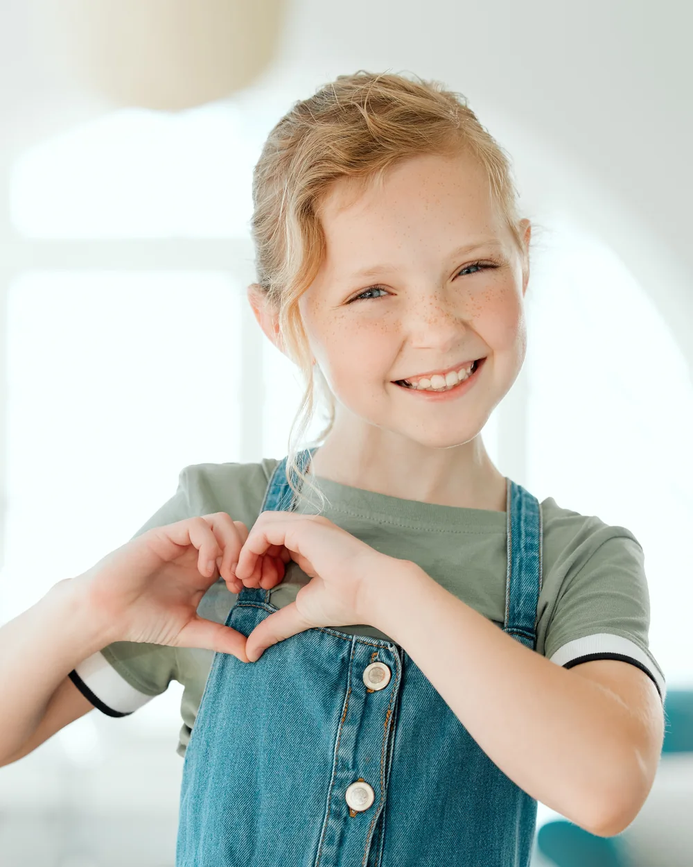 Smiling child making a heart shape with her hands