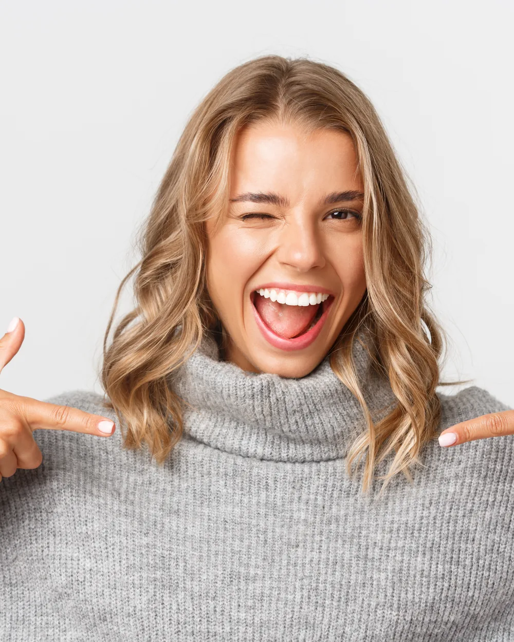 Smiling woman pointing toward her smile